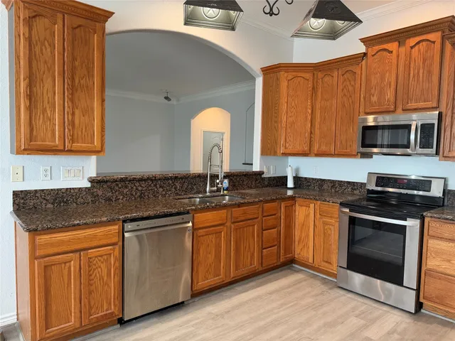 a kitchen with granite countertop wood cabinets stainless steel appliances and a sink