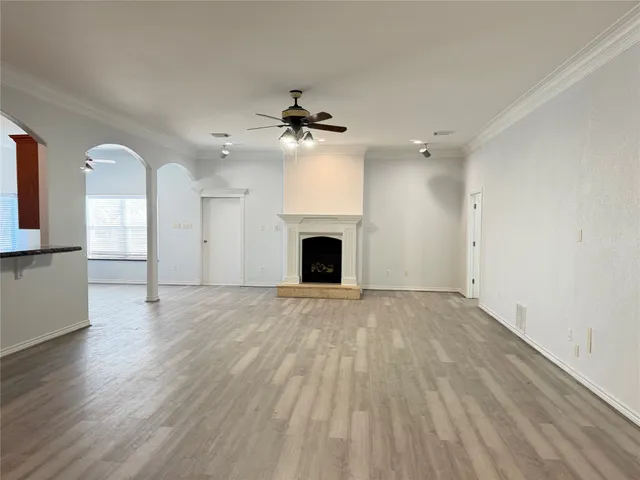 an empty room with fireplace wooden floor and chandelier