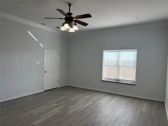 an empty room with wooden floor chandelier fan and windows