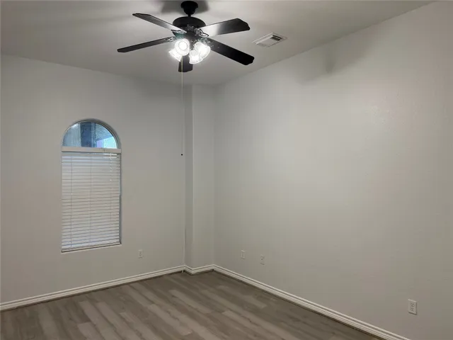 an empty room with a window and a fan