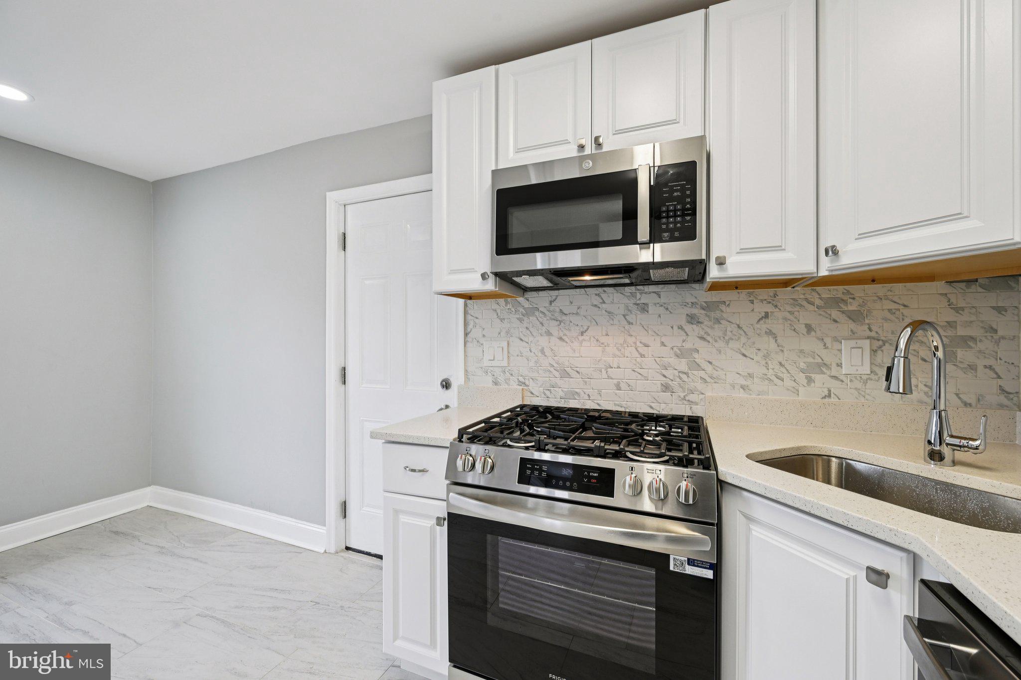 4902 Gilray Drive Baltimore, MD 21214 - Photo 19 of 54 a kitchen with stainless steel appliances white cabinets and a stove top oven