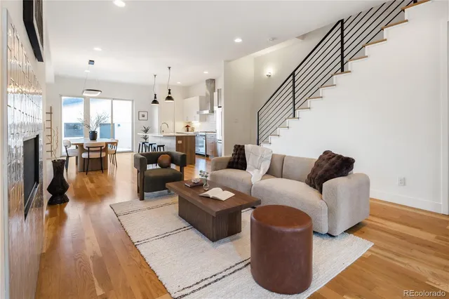 a living room with furniture kitchen view and a wooden floor