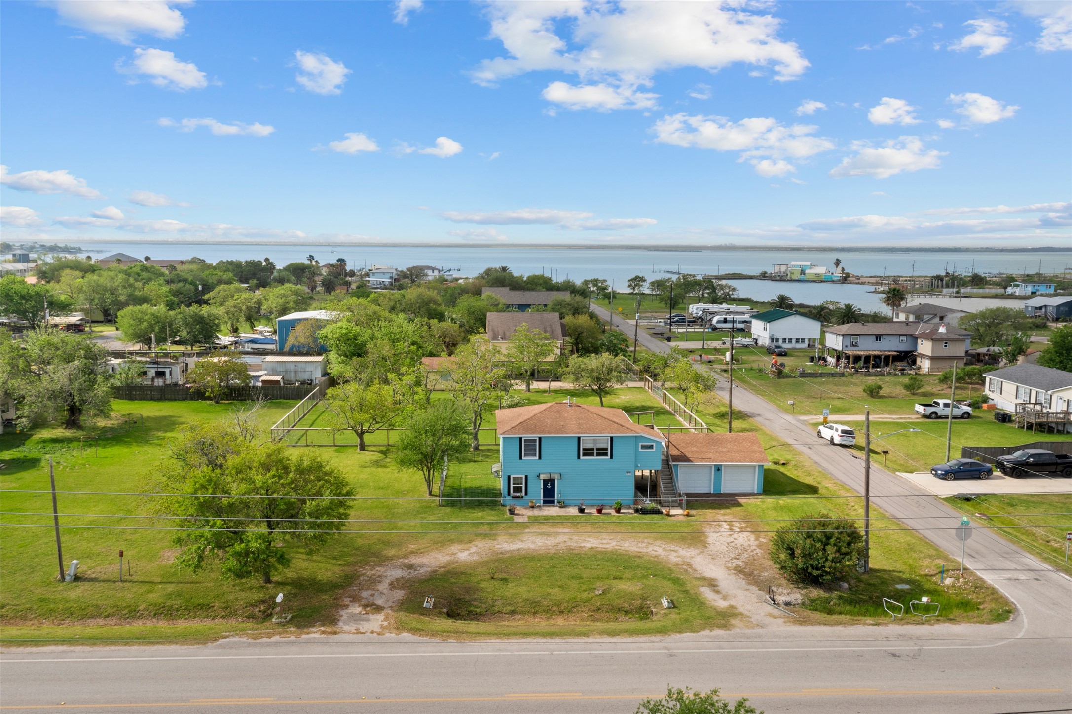 1619 FM 517 Road East San Leon, TX 77539 - Photo 2 of 27 This photo showcases a spacious lawn, set in a peaceful neighborhood. Clear view of the water in the background, offering a serene and picturesque setting. Ideal for those seeking a tranquil location with easy access to scenic waterfront views.