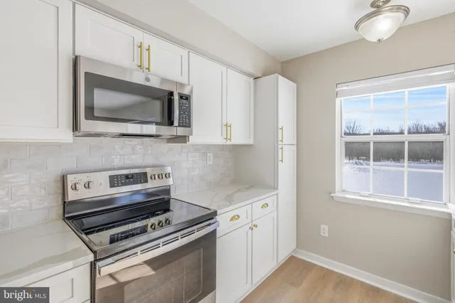 a kitchen with cabinets stainless steel appliances and a window