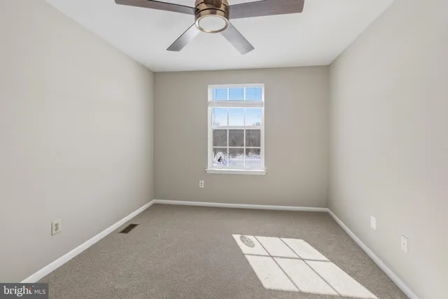 an empty room with a ceiling fan and window