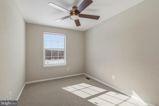 an empty room with a window and a fan