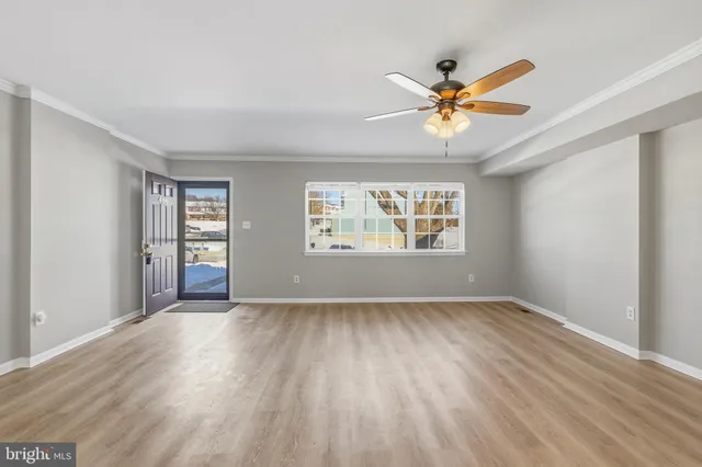 a view of an empty room with window and wooden floor