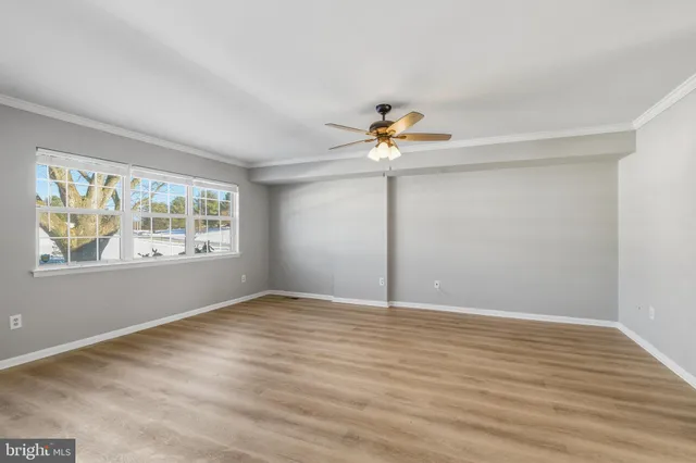a view of an empty room with a window and wooden floor