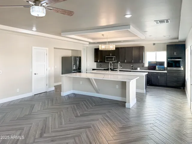 a large white kitchen with kitchen island a stove a sink dishwasher and white cabinets with wooden floor