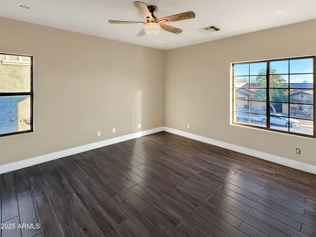 an empty room with wooden floor and windows