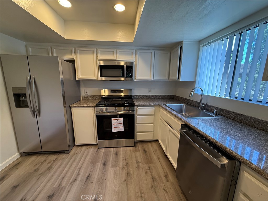 5250 Colodny Drive, Unit 17 Agoura Hills, CA 91301 - Photo 7 of 17 a kitchen with stainless steel appliances a sink dishwasher a refrigerator a stove top oven a sink and dishwasher with wooden floor