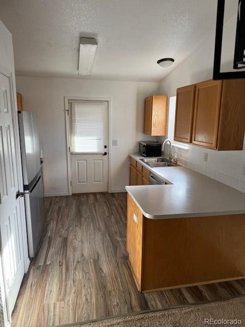 304 Sunset Lane Dacono, CO 80514 - Photo 5 of 22 a kitchen with a sink a refrigerator and wooden floor