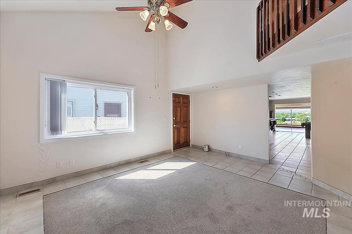2804 West Sunrise Rim Road Boise, ID 83705 - Photo 23 of 50 Spacious living area featuring vaulted ceilings, a wood-paneled ceiling fan, a large window, a wood entry door, and a tiled floor entry area
