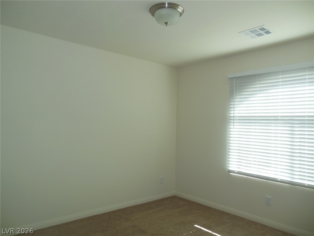 6390 Jackson Spring Road Las Vegas, NV 89118 - Photo 23 of 27 A well-lit, neutral-toned room features soft carpeting and a window with horizontal blinds.