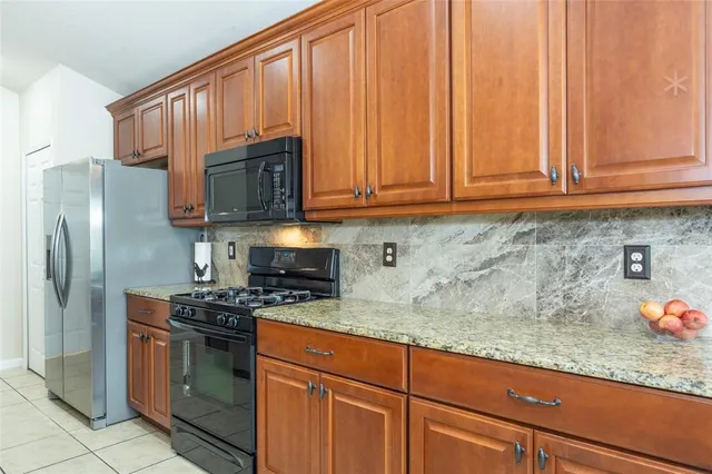 a kitchen with granite countertop stainless steel appliances a stove a refrigerator a sink and cabinets