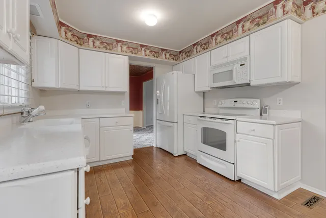 a kitchen with white cabinets and white appliances