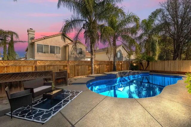 a view of a backyard with swimming pool and sitting area