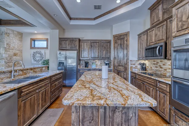 a large kitchen with kitchen island granite countertop a large counter top stainless steel appliances and cabinets