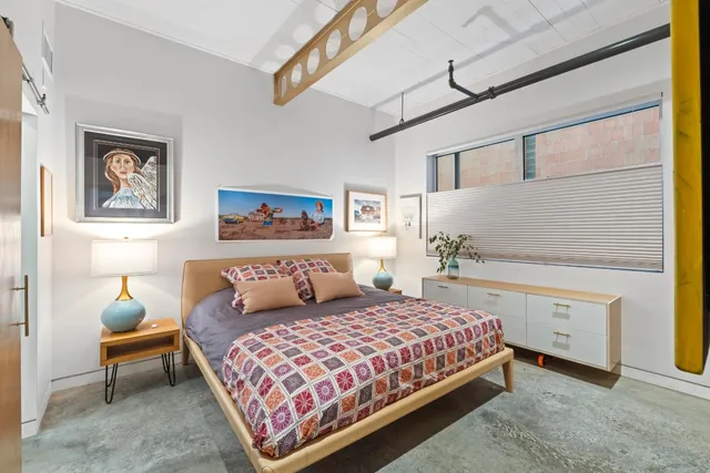 a bedroom with a bed and painting on the wall