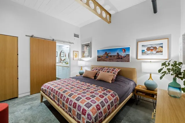 a bedroom with a bed wall painting and a window