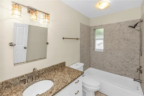 a bathroom with a granite countertop sink mirror and a toilet