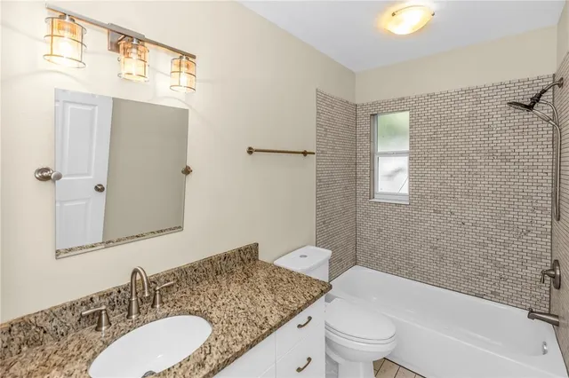 a bathroom with a granite countertop sink toilet a mirror and shower
