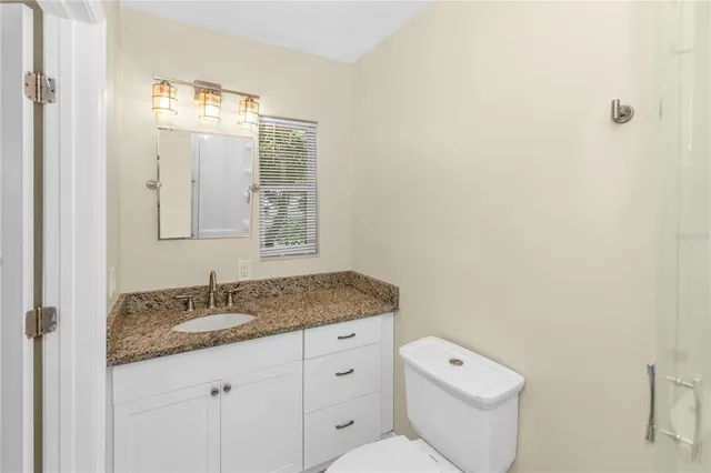 a bathroom with a granite countertop sink mirror and a toilet