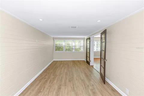 an empty room with wooden floor and a ceiling fan