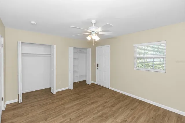 an empty room with wooden floor and a ceiling fan