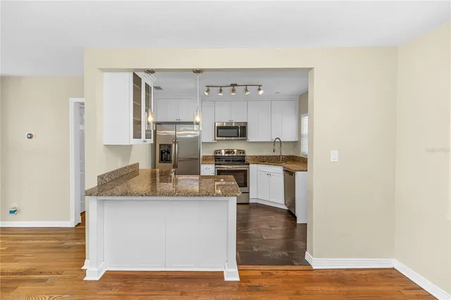 a view of a kitchen with kitchen island a counter top space cabinets and stainless steel appliances