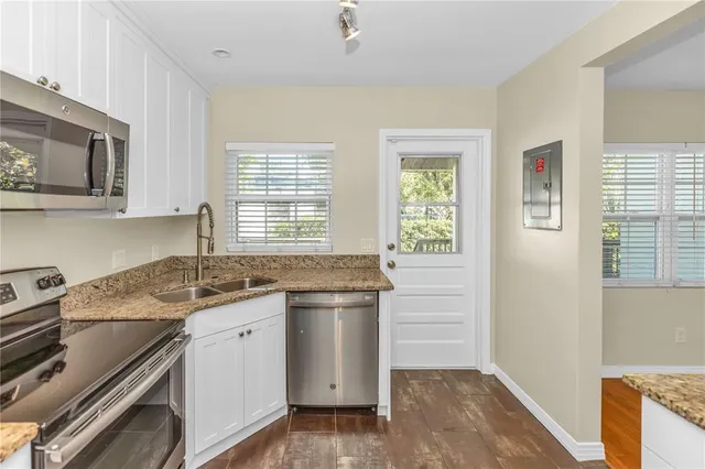 a kitchen with granite countertop stainless steel appliances a sink stove and cabinets