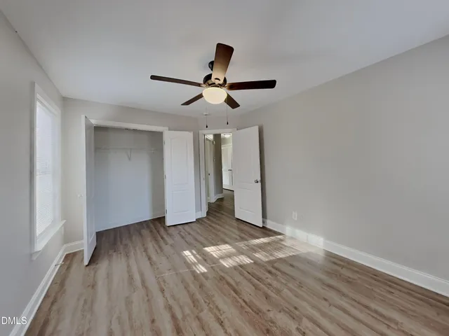 a view of empty room with wooden floor and fan