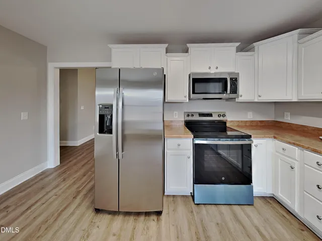 a kitchen with stainless steel appliances granite countertop white cabinets a microwave a sink and a refrigerator
