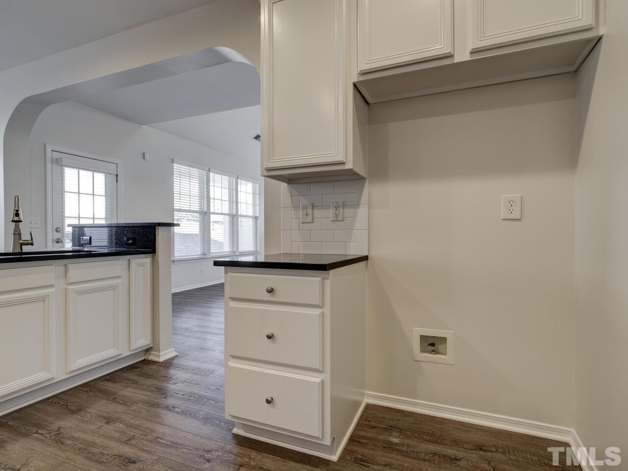8219 Beaded Stone Street Raleigh, NC 27613 - Photo 12 of 45 a kitchen with white cabinets and wooden floor