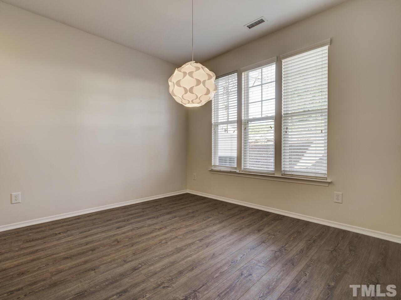 8219 Beaded Stone Street Raleigh, NC 27613 - Photo 15 of 45 an empty room with wooden floor and windows