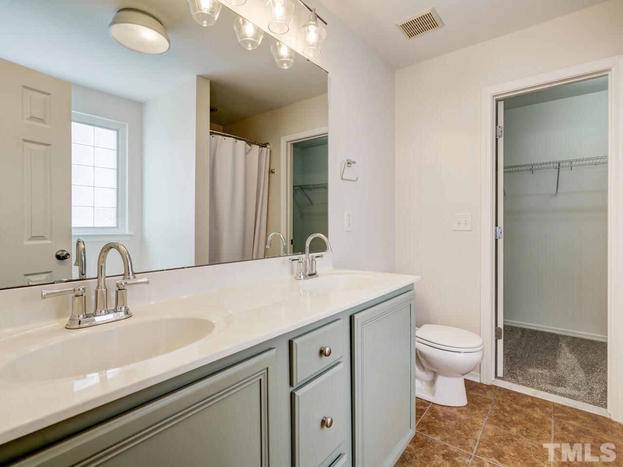 8219 Beaded Stone Street Raleigh, NC 27613 - Photo 24 of 45 a bathroom with a sink a toilet a large mirror and shower