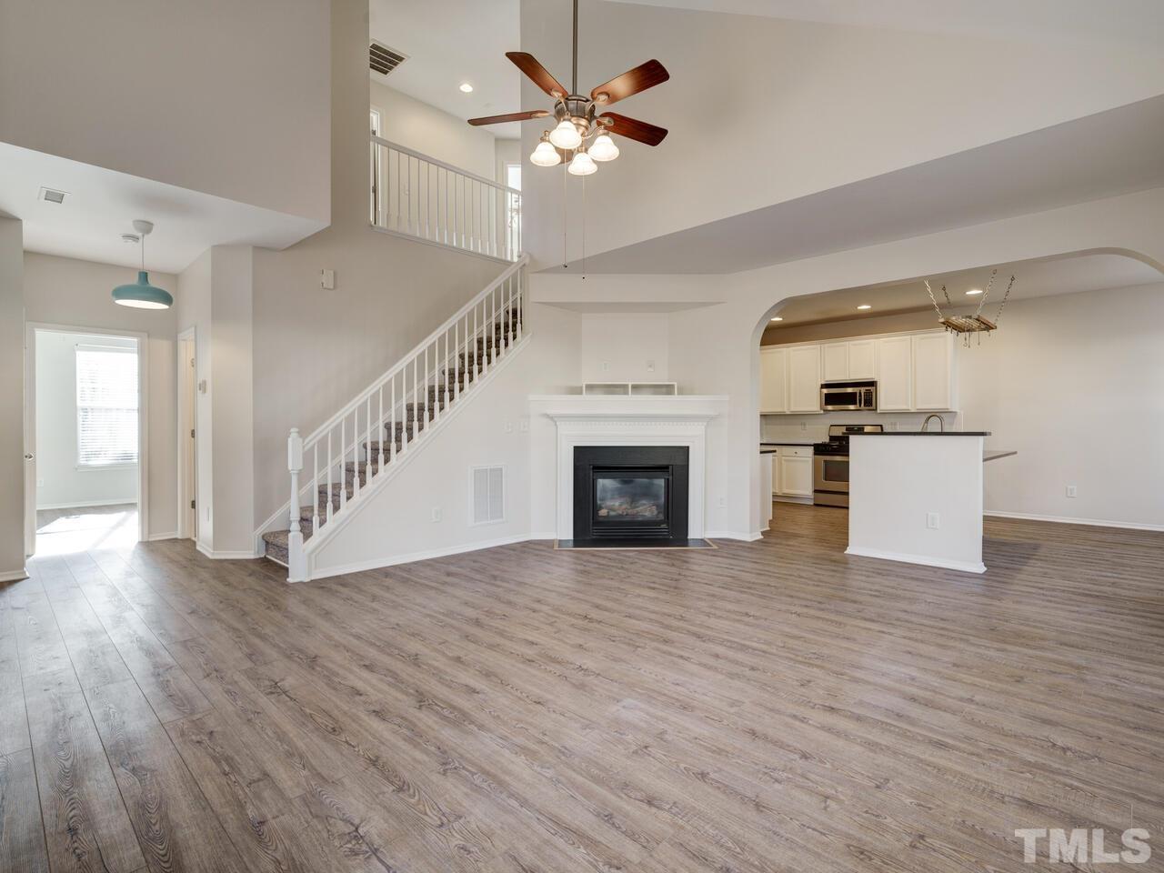 8219 Beaded Stone Street Raleigh, NC 27613 - Photo 7 of 45 a view of a livingroom with a ceiling fan a kitchen wooden floor and a ceiling fan