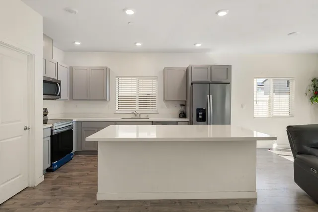 a large kitchen with stainless steel appliances a large counter top a refrigerator and a sink