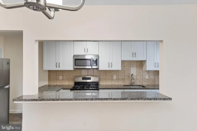 a kitchen with stainless steel appliances granite countertop a sink a stove a microwave and cabinets