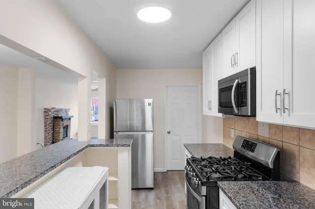 a kitchen with stainless steel appliances granite countertop a stove a sink and a refrigerator