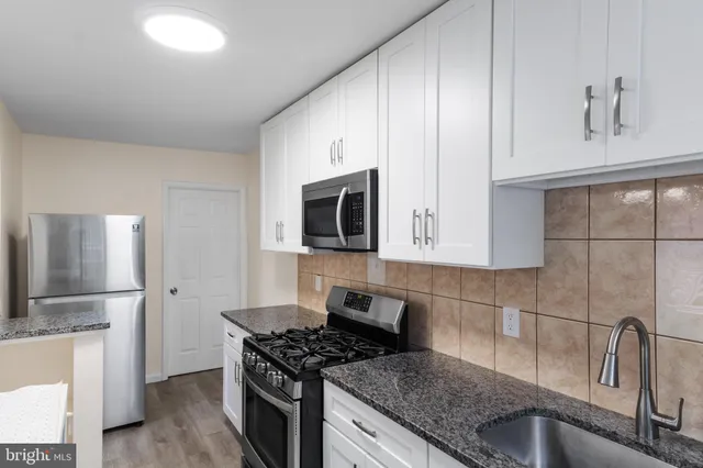 a kitchen with stainless steel appliances granite countertop a sink stove and microwave