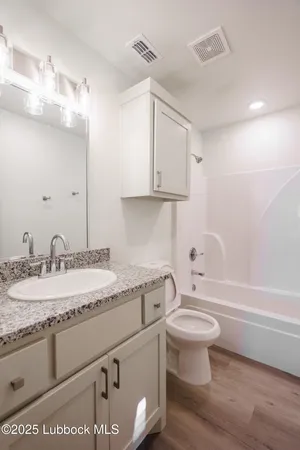 a bathroom with a granite countertop sink a toilet and bathtub