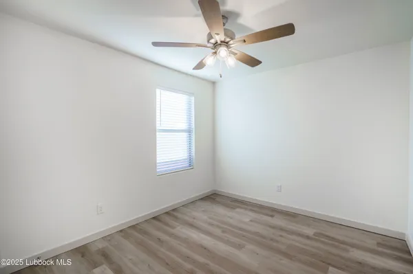 an empty room with a window and a fan