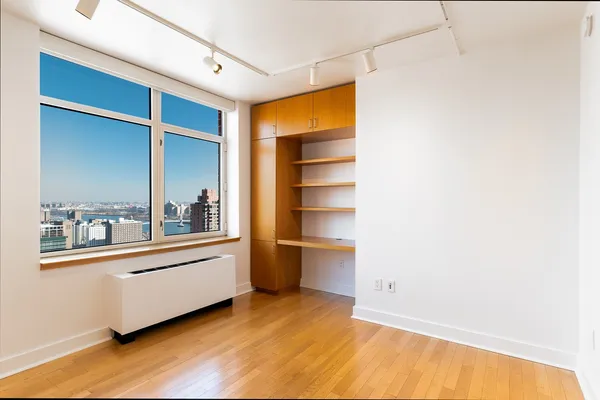 a view of an empty room with closet and a window