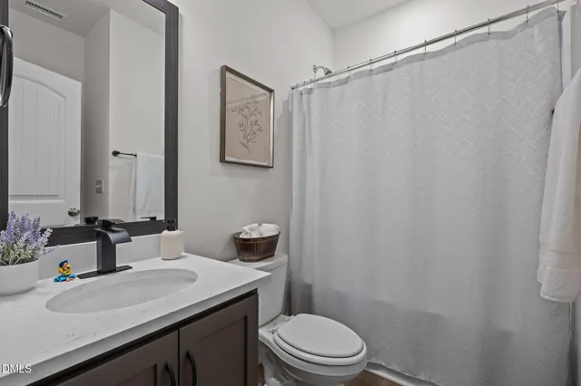 a bathroom with a sink a toilet a mirror and shower curtain