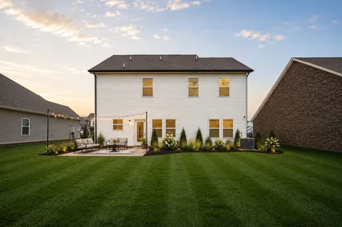 a front view of a house with a garden and lake view