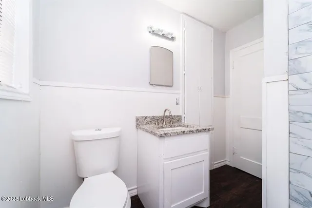 a bathroom with a granite countertop toilet sink and mirror