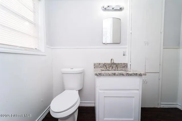 a bathroom with a toilet sink vanity and mirror