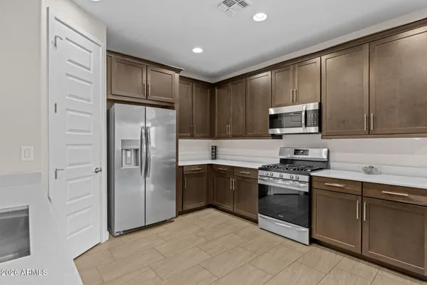 a kitchen with stainless steel appliances kitchen island granite countertop a table chairs sink and cabinets