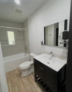 a bathroom with a double vanity sink toilet mirror and bathtub